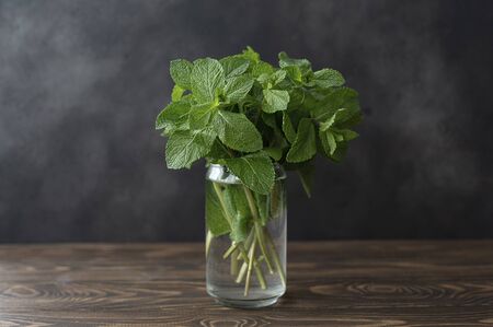 sprigs of fresh large green mint on a wooden board