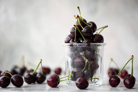 Ripe black cherries on branch in a glass cup
