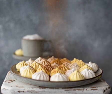 white and yellow meringues with coffee and cinnamonの写真素材
