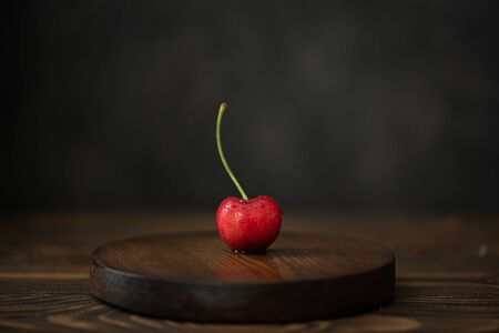 red cherries with a branch on a wooden board