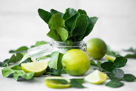 lime leaves in jar and ripe limes on a white tableの写真素材