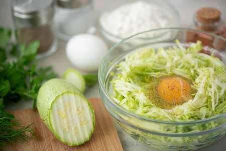 Grated zucchini with raw egg, greens and spices for making squash frittersの写真素材