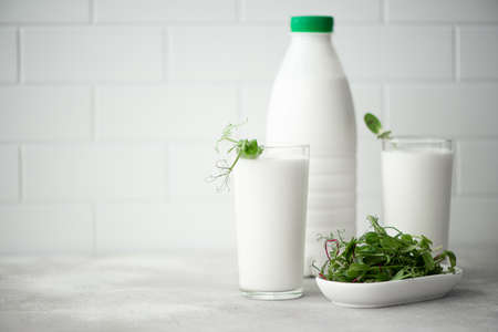 fresh kefir in a plastic bottle and glass with microgreens