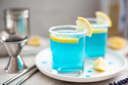 blue curacao cocktail with lemon slices in glasses on white plateの写真素材