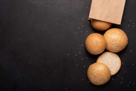round small buns with sesame seeds in a craft bag, top view