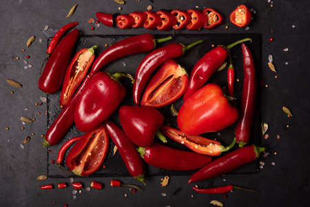 red bell pepper and hot peppers on black board, top view