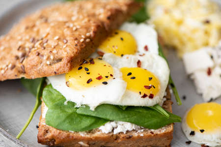 sandwich with quail eggs, curd cheese and spinach on a gray plate
