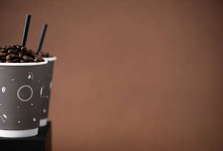 two craft coffee cups with coffee beans on brown backgroundsの写真素材