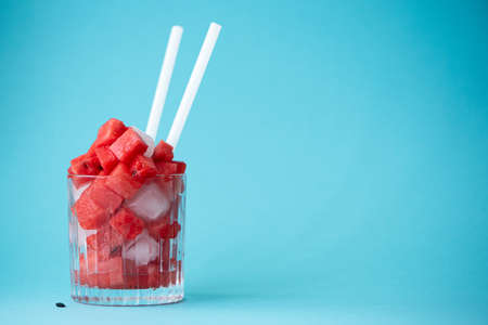 red ripe watermelon cut into pieces in a glass on a blue backgroundの写真素材