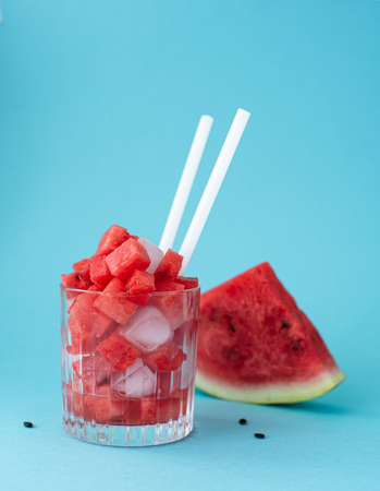 red ripe watermelon cut into pieces in a glass on a blue backgroundの写真素材
