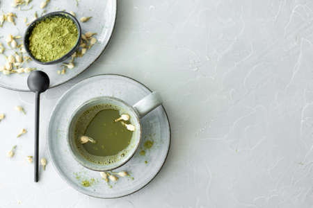 green matcha in a gray ceramic cup on white table