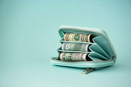 turquoise wallet with money on a light blue backgroundの写真素材