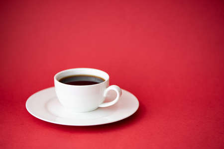 black coffee in a small white coffee cup on a red backgroundの写真素材