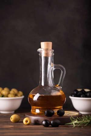 olive oil in a glass bottle with olives, herbs and spices