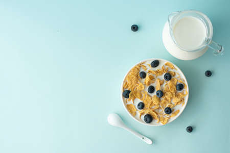 cornflakes with milk and blueberries on a blue background