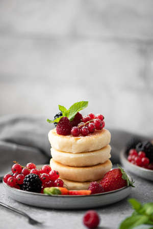 cottage cheese pancakes with fresh berries and mint on a gray plateの写真素材