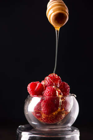 ripe raspberries in a glass bowl poured with honey