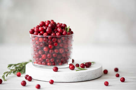 ripe lingonberries in a glass bowl on a white boardの写真素材