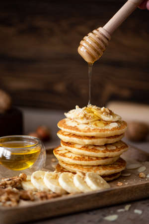 small pancakes with banana, walnuts and honey on a wooden tray