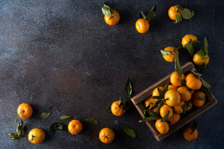 ripe tangerines with leaves in a wooden box, top viewの写真素材