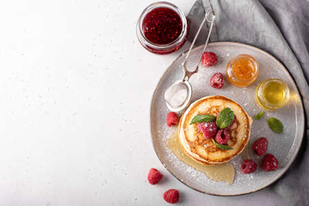 homemade lush pancakes with raisins and honey on a gray plate, top viewの写真素材
