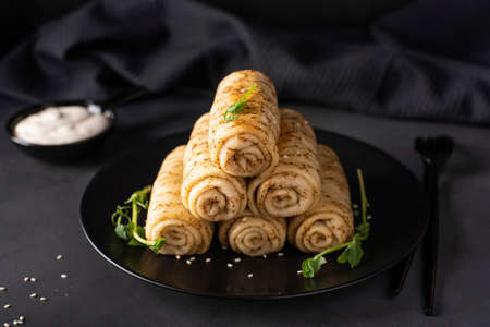 homemade pancakes with meat filling on a black plate, close-upの写真素材
