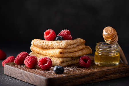 thin homemade pancakes with berries and honey, close-upの写真素材
