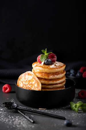 small thin pancakes with fresh berries and honey in a black bowl, close-upの写真素材
