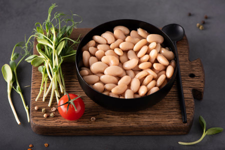 boiled white beans with spices and herbs in a black bowl, close-upの写真素材