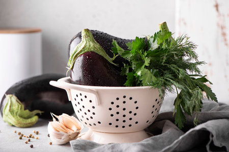 large eggplants with garlic, parsley and dill in a white colander, close upの写真素材