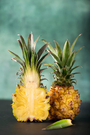 fresh cut mini pineapple on green background, close-up