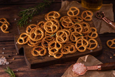 small salted pretzels with salt and spices on a wooden board, close-up