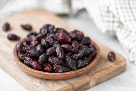 dried berries of large wild roses in a wooden bowl, close-upの写真素材
