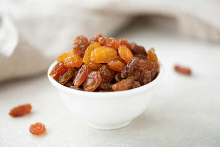 large raisins from black grapes in a white bowl, close-upの写真素材