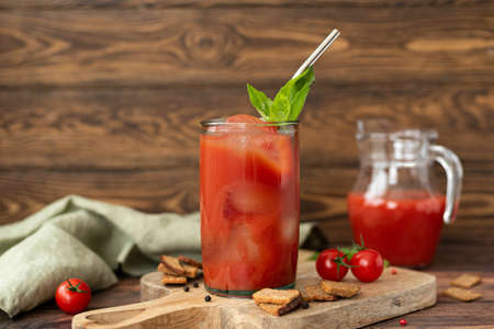 tomato juice with basil and croutons in a glass on a wooden table, close-upの写真素材
