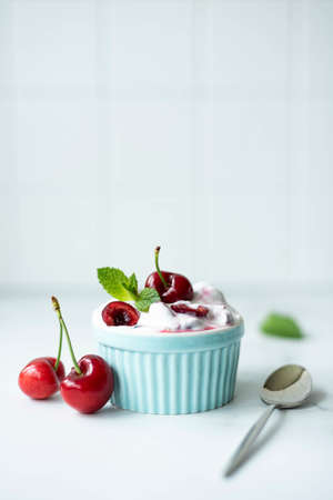 large cherries with greek yogurt and mint in a blue bowl, close-upの写真素材