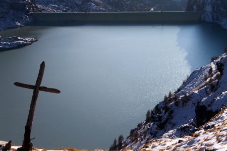 Mountain lake with a cross and snow in Northern Italyの写真素材