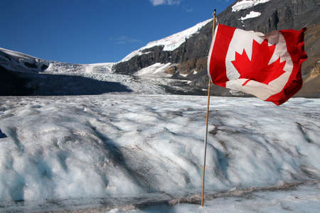 Waving red Canadian flag on the melting Athabasca glacier in Jasper National Parkの写真素材