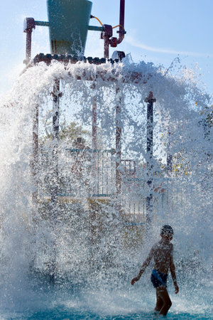 Attraction in the water park. From a large bucket poured a lot of water. Child under water streamの写真素材