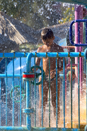 Teen Boy in the water park, surrounded by lots of fountains and sprayのeditorial素材