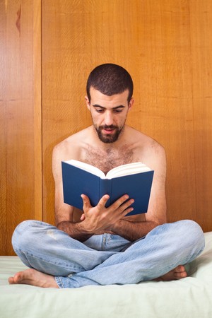 man reading a book on the bedの写真素材