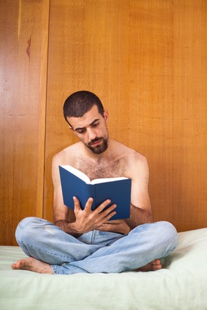 man reading a book on the bedの写真素材