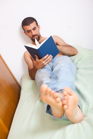 man reading a book on the bedの写真素材