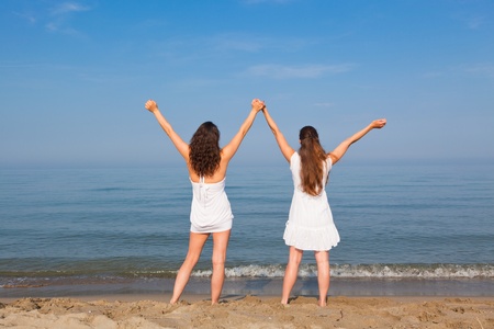 Two Young Women with Arms Outstretched on Seasideの写真素材