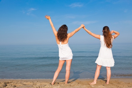 Two Young Women with Arms Outstretched on Seasideの写真素材