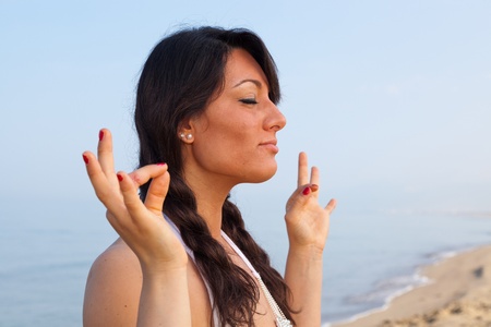 Beautiful Young Woman Doing Yoga Exercises at Seasideの写真素材