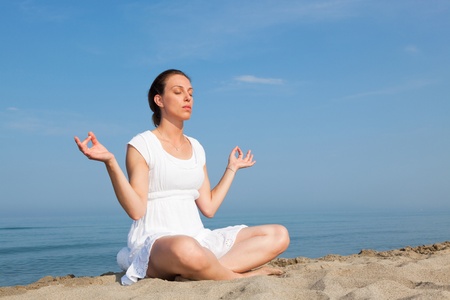 Beautiful Young Woman Doing Yoga Exercises at Seasideの写真素材