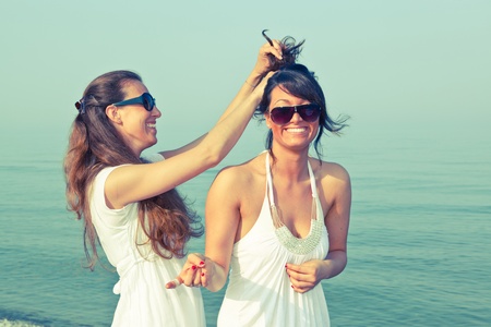 Young Woman Dress Her Friend's Hairs at Seasideの写真素材
