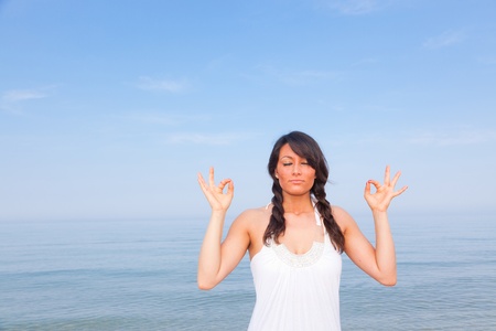 Beautiful Young Woman Doing Yoga Exercises at Seasideの写真素材