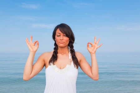 Beautiful Young Woman Doing Yoga Exercises at Seasideの写真素材